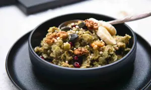 Grüner, cremiger matcha porridge mit Nüssen, Kernen, Granatapfel und Bananenscheiben. Ein gesundes Frühstück.
