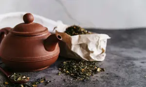 Braune Teekanne mit losem Tee und einem Löffel, bereit für den Aufguss Tee.