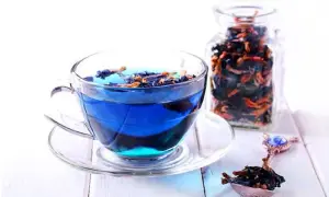 Blauer Tee aus Clitoria ternatea, bekannt für seine Wirkung, in einer Tasse und einem Glasbehälter.