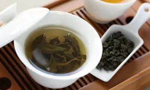 Eine Tasse Oolong Tee, daneben trockene Blätter. Wie viel Oolong Tee am Tag ist gesund?
