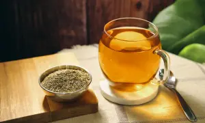 Eine Tasse goldener Thymiantee steht neben einer Schale getrocknetem Thymian. Die beruhigende Thymiantee Wirkung ist spürbar.