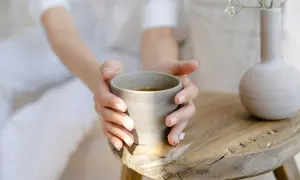Sanfte Hände halten eine Tasse Tee. Ein Moment der Ruhe, perfekt, um abends Brennnesseltee zu trinken.