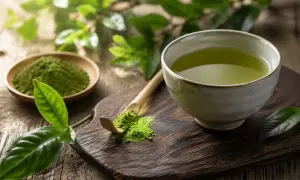 Grüner Tee mit Coffein in Tee, zubereitet aus feinem Pulver auf einem Holzbrett.
