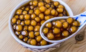 Ein Schälchen mit braunen Tapiokaperlen, perfekt für ein leckeres Boba-Rezept. Eine Löffel voller Perlen zeigt die köstliche Textur.