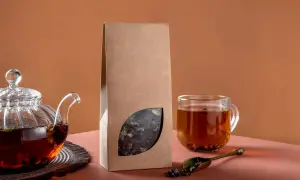 Glas-Teekanne mit braunem Tee, eine Packung mit losem Blatt-Tee und eine Tasse Tee. Perfekt für selbstgemachten Tee.