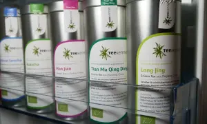 Reihe von Teedosen, die verschiedene Teesorten wie Sencha, Kukicha, Mao Jian, Tian Mu Qing Ding und Long Jing lagern.