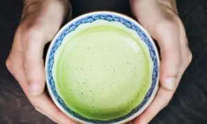 Hände halten eine Schale mit schaumigem, leuchtend grünem Matcha. Für manche ist Matcha ein Genuss, für andere ein Thema bei Histaminintoleranz.