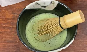 Ein Chasen rührt schaumigen Usucha Matcha in einer Schale.