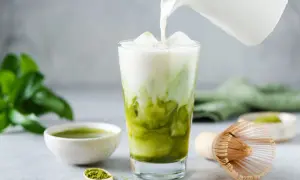 Milch wird in ein Glas mit Eis und Matcha gegossen. Ein einfaches Matcha Latte Rezept für den perfekten Genuss.