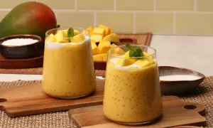Zwei Gläser cremiger Mango-Bubble-Tea mit Tapiokaperlen, garniert mit frischen Mangostücken und Minze. Ein Mango-Rezept zum Genießen.