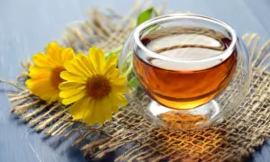 Zwei gelbe Blumen neben einer Tasse Tee. Zeit, dass das muss teewasser kochen für einen entspannenden Moment.