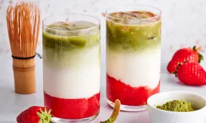 Zwei Schichten-Getränke mit Erdbeerpüree, Milch und Matcha. Ein Chasen und frische Erdbeeren deuten an, was ist eigentlich in rotem Matcha drin.
