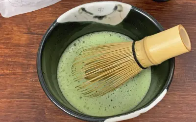 Ein Chasen rührt schaumigen Usucha Matcha in einer Schale.