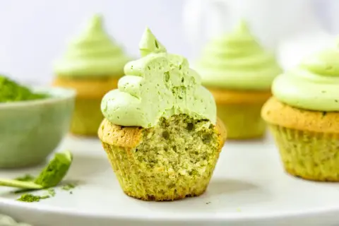 Saftige matcha cupcakes mit fluffigem Topping. Ein Bissen verrät die köstliche grüne Füllung.