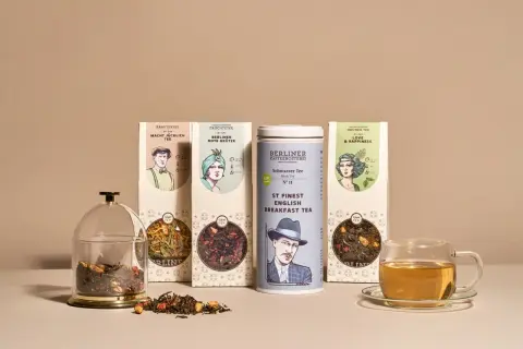 Verschiedene Teesorten alphabetisch geordnet: Kräutertee, aromatisierter Früchtetee, schwarzer Tee und grüner Tee. Daneben eine Teetasse mit Aufguss.