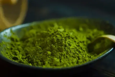 Feines, leuchtend grünes Matcha-Pulver in einer Schale, bereit für einen Energieschub durch den enthaltenen Matcha-Koffein.