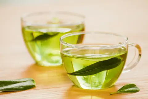 Zwei Gläser mit grünem Tee, welcher Tee regt den Stoffwechsel an? Grüner Tee mit Blättern.