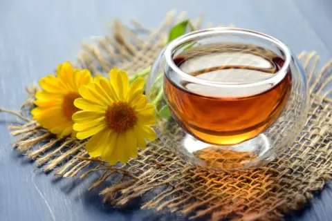 Zwei gelbe Blumen neben einer Tasse Tee. Zeit, dass das muss teewasser kochen für einen entspannenden Moment.