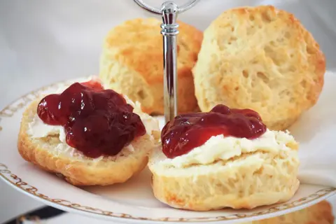 Zwei Scones mit Clotted Cream und Marmelade auf einer Etagere, perfekt für ein Cream Tea Rezept.