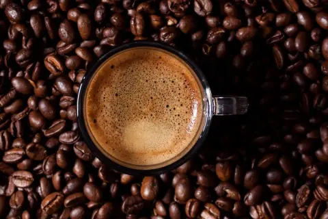 Eine Tasse Espresso auf gerösteten Kaffeebohnen. Wenn zu viel Koffein im Spiel ist, hilft Wasser und Geduld.