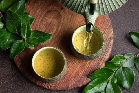 Grüner Tee wird in zwei Schalen gegossen. Welcher Tee ist antibakteriell? Grüner Tee ist bekannt für seine gesundheitlichen Vorteile.