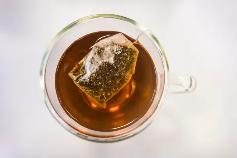 Eine Tasse Tee mit Teebeutel. Die klare Flüssigkeit und der Teebeutel lassen die ctc bedeutung erahnen: ein starker, aromatischer Genuss.