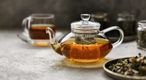 Glas-Teekanne mit schwarzem Tee, der dampft. Ist schwarzer Tee gut zum Abnehmen? Ja, er kann helfen.