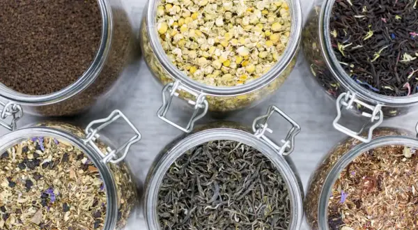 Sechs Gläser mit verschiedenen blattgrad tee Sorten: Kamille, schwarzer Tee, grüner Tee, Rooibos und Kräutermischungen.