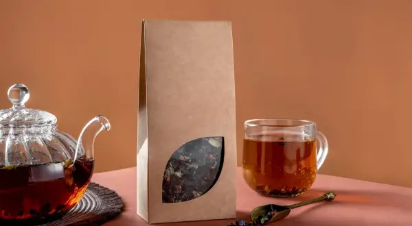 Glas-Teekanne mit braunem Tee, eine Packung mit losem Blatt-Tee und eine Tasse Tee. Perfekt für selbstgemachten Tee.
