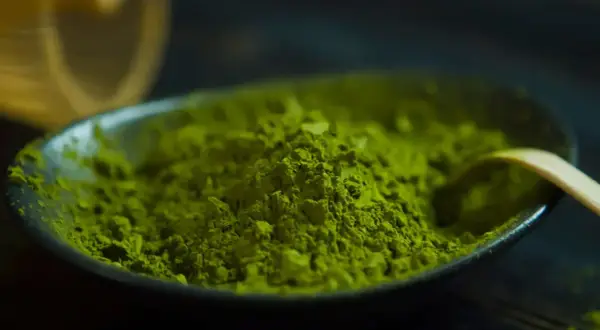 Feines, leuchtend grünes Matcha-Pulver in einer Schale, bereit für einen Energieschub durch den enthaltenen Matcha-Koffein.