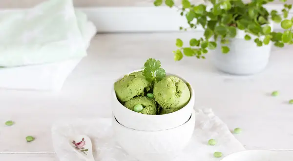 Schalen mit cremigem Matcha-Eis, garniert mit Koriander und Erbsen. Ein erfrischender Genuss!