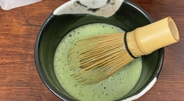 Ein Chasen rührt schaumigen Usucha Matcha in einer Schale.