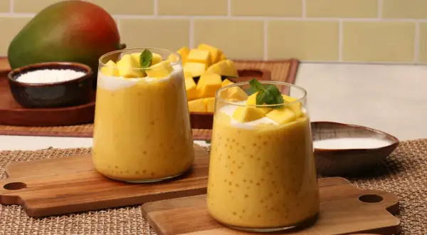 Zwei Gläser cremiger Mango-Bubble-Tea mit Tapiokaperlen, garniert mit frischen Mangostücken und Minze. Ein Mango-Rezept zum Genießen.