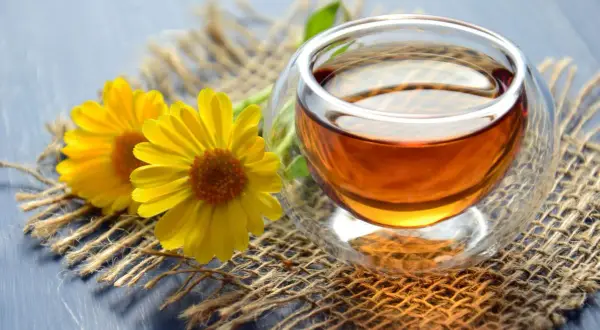 Zwei gelbe Blumen neben einer Tasse Tee. Zeit, dass das muss teewasser kochen für einen entspannenden Moment.