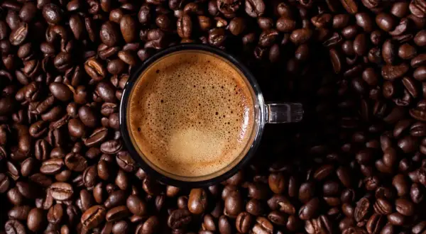 Eine Tasse Espresso auf gerösteten Kaffeebohnen. Wenn zu viel Koffein im Spiel ist, hilft Wasser und Geduld.