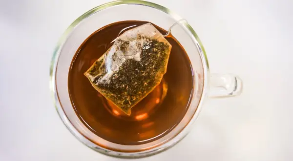Eine Tasse Tee mit Teebeutel. Die klare Flüssigkeit und der Teebeutel lassen die ctc bedeutung erahnen: ein starker, aromatischer Genuss.