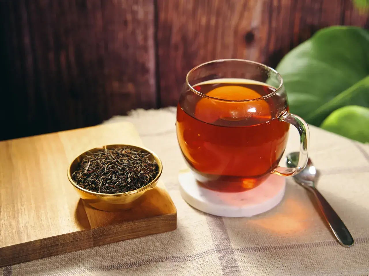 Eine Tasse heißer Ceylon Tee, reich an Koffein, neben einer Schale trockener Teeblätter.
