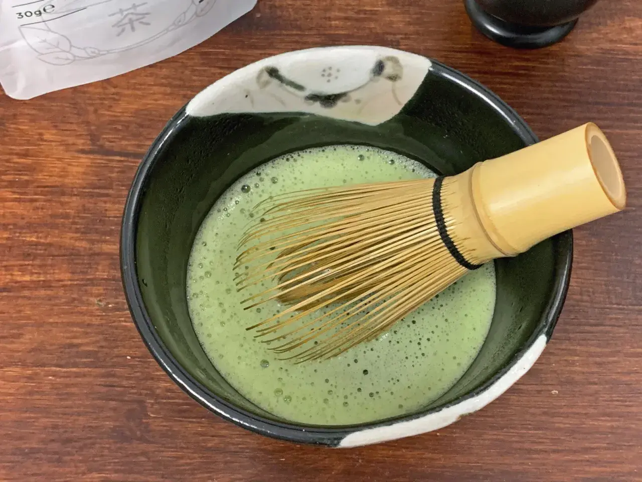Ein Chasen rührt schaumigen Usucha Matcha in einer Schale.