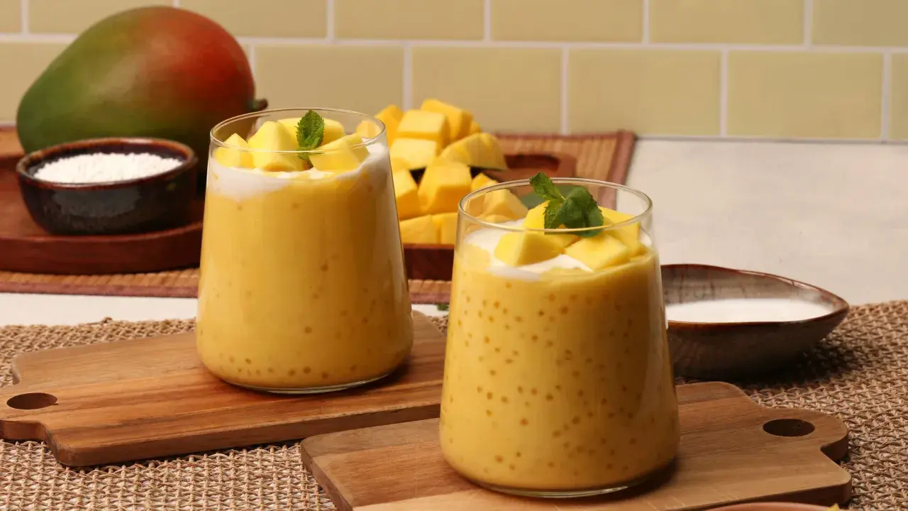 Zwei Gläser cremiger Mango-Bubble-Tea mit Tapiokaperlen, garniert mit frischen Mangostücken und Minze. Ein Mango-Rezept zum Genießen.