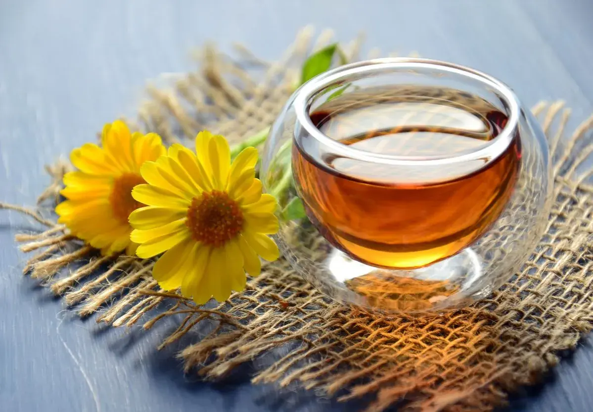 Zwei gelbe Blumen neben einer Tasse Tee. Zeit, dass das muss teewasser kochen für einen entspannenden Moment.