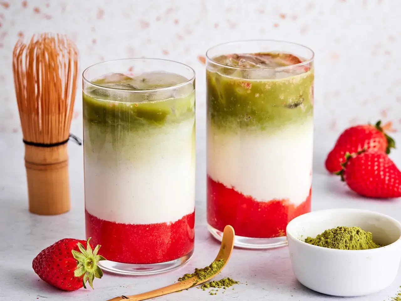 Zwei Schichten-Getränke mit Erdbeerpüree, Milch und Matcha. Ein Chasen und frische Erdbeeren deuten an, was ist eigentlich in rotem Matcha drin.