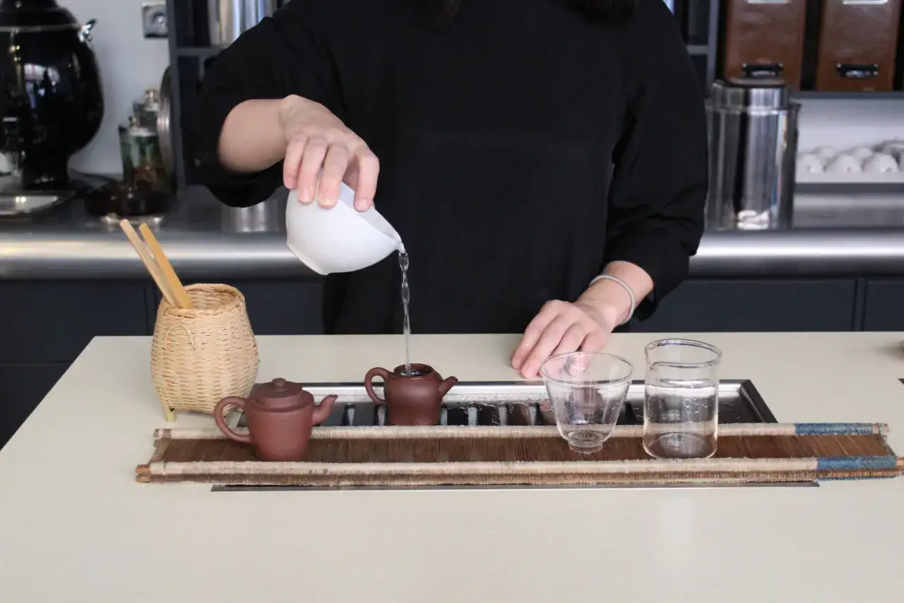 Eine Person gie&szlig;t Wasser in eine kleine Teekanne f&uuml;r Pu-erh-Tee. Der Tee ist bekannt f&uuml;r seinen Koffeingehalt.