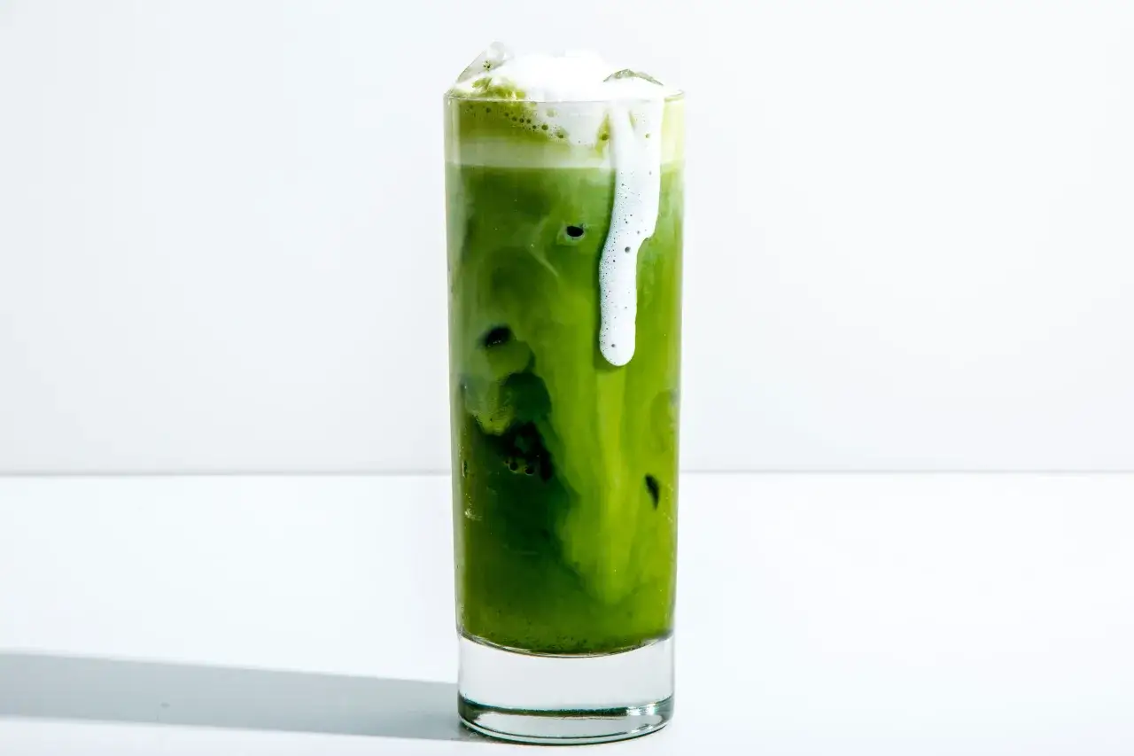 Ein erfrischender iced matcha mit cremigem Schaum, der &uuml;ber den Rand des Glases l&auml;uft.