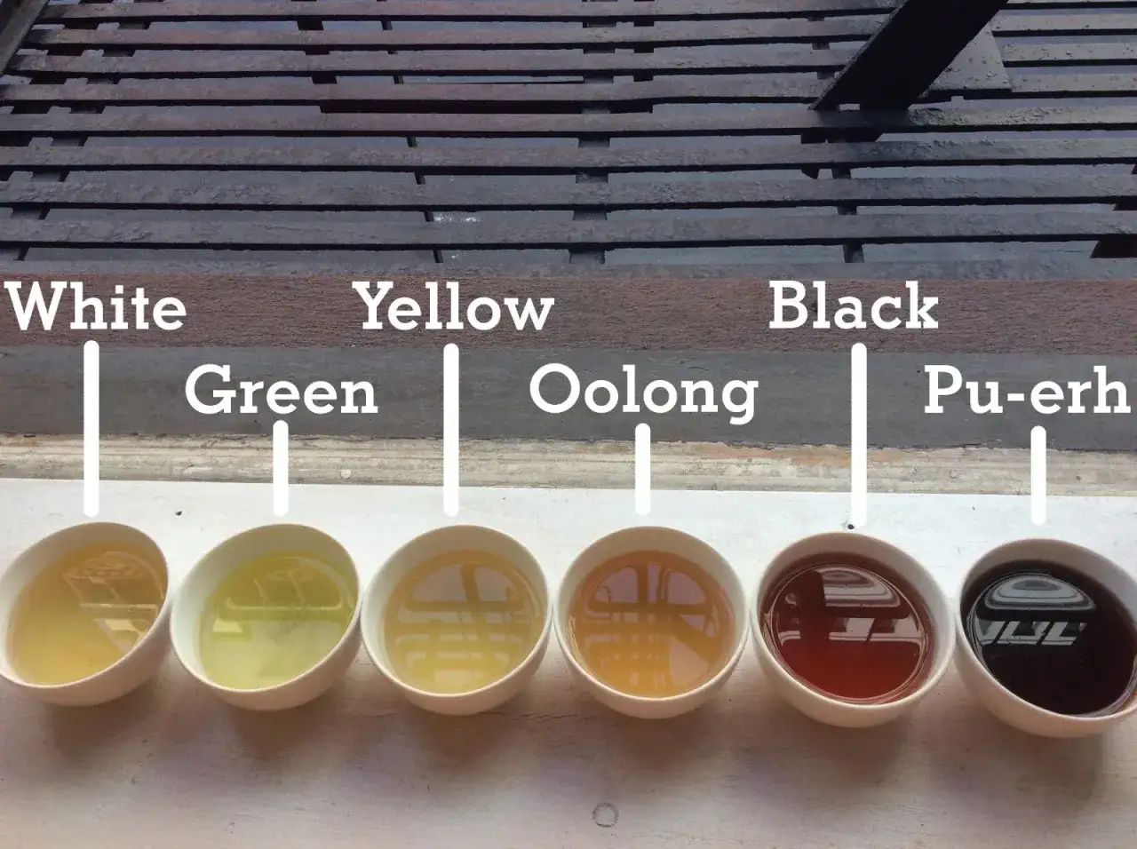 Sechs Schalen mit Tee: Wei&szlig;, Gr&uuml;n, Gelb, Oolong, Schwarz und Pu-erh. Die Pu-erh tee wirkung ist oft belebend.