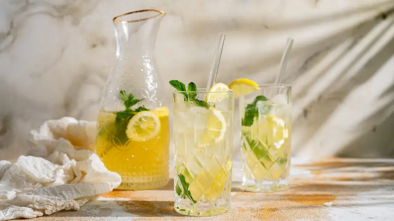 Erfrischender Minztee selber machen: Karaffe und Gl&auml;ser gef&uuml;llt mit Zitronenlimonade, Eis, Minze und Zitronenscheiben.