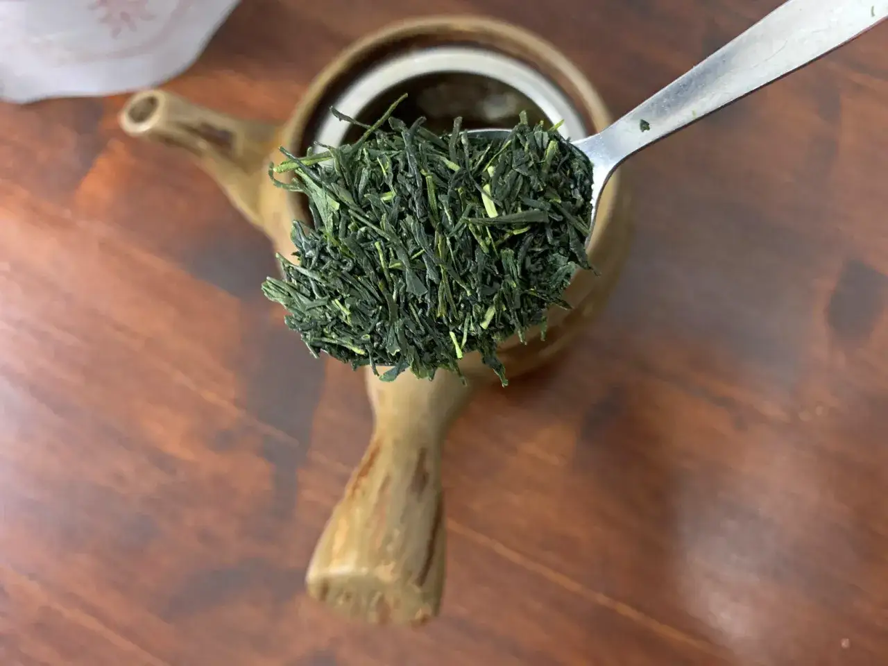 Ein L&ouml;ffel voller gr&uuml;ner Teebl&auml;tter f&uuml;r die Sencha Tee Zubereitung, bereit f&uuml;r die Kanne.
