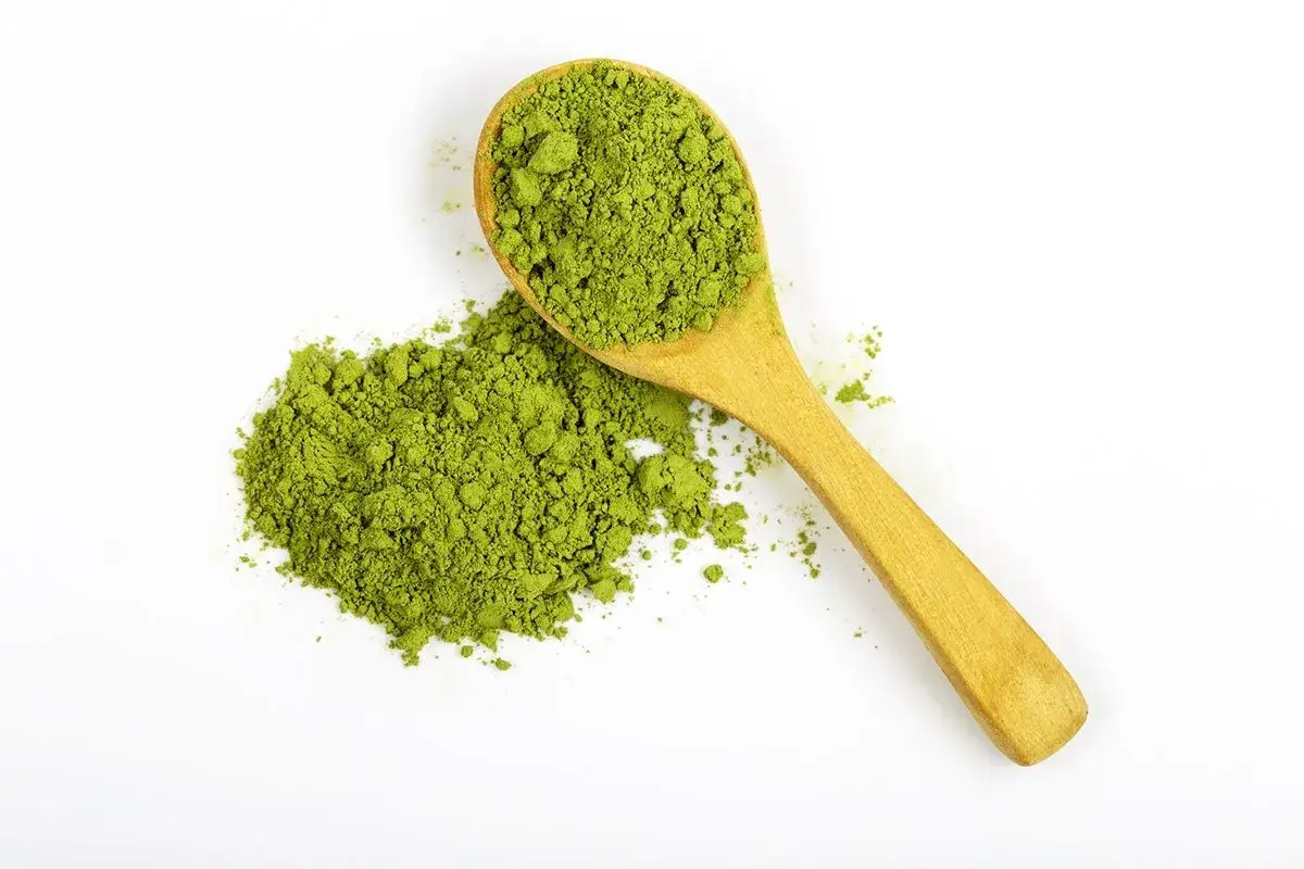 Ein Holzlöffel mit feinem, grünem Matcha-Pulver. Die positive matcha wirkung darm wird oft für seine gesundheitlichen Vorteile geschätzt.