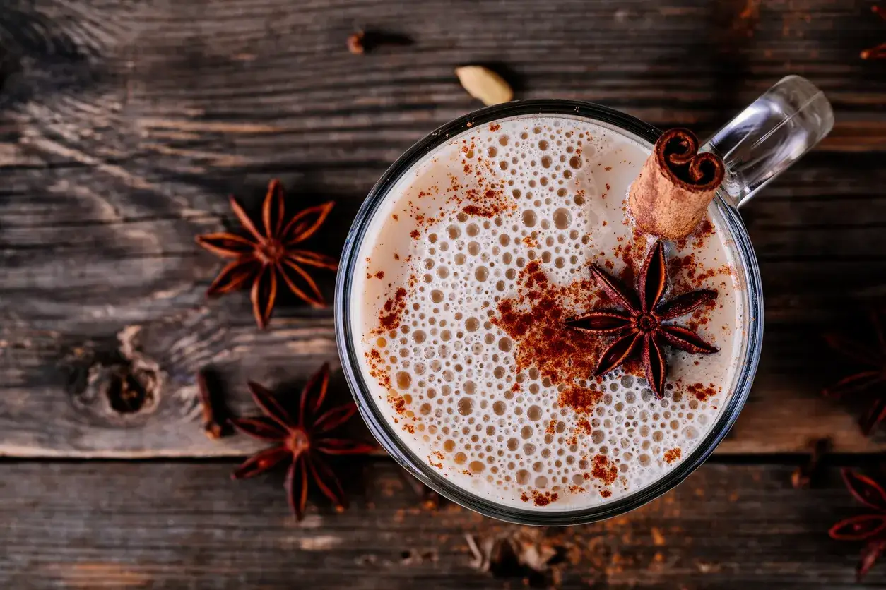 Ein Glas cremiger Chai Latte, garniert mit Sternanis und Zimt. Das perfekte indischer chai rezept f&uuml;r gem&uuml;tliche Momente.