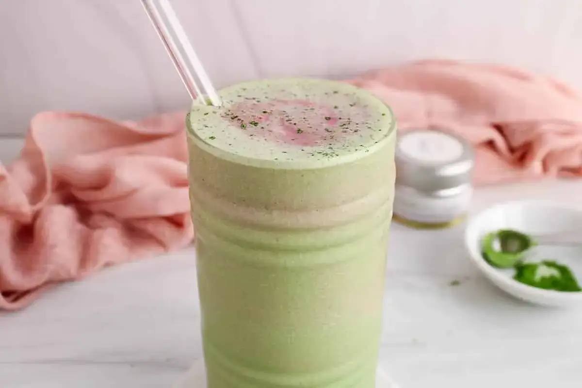 Ein cremiger, grüner Matcha Smoothie mit einer Prise Pulver obendrauf, bereit zum Genießen.