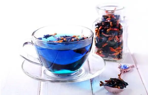 Blauer Tee aus Clitoria ternatea, bekannt für seine Wirkung, in einer Tasse und einem Glasbehälter.